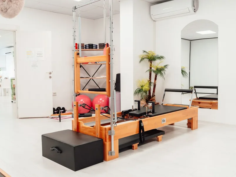 A bright white Pilates studio with reformer equipment