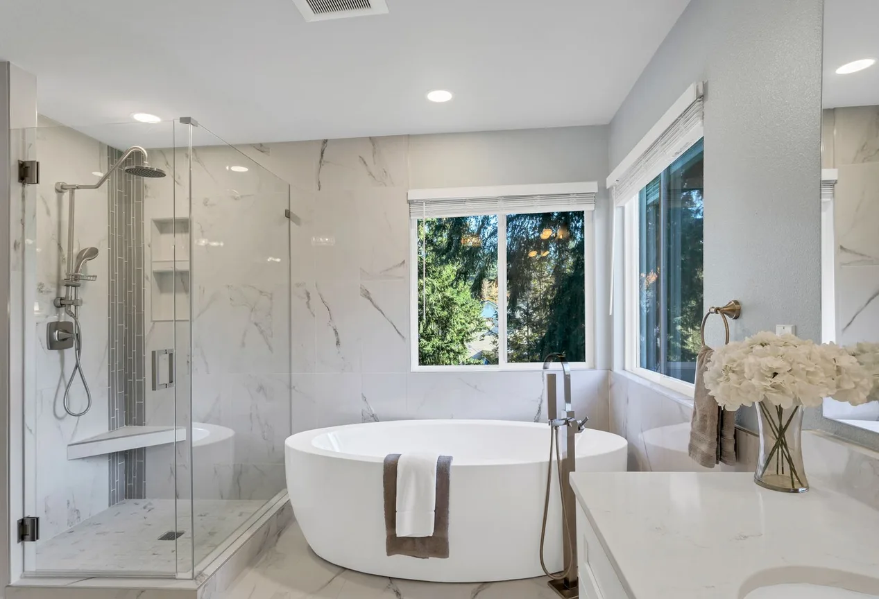 A marble bathroom with a freestanding tub and fresh flowers