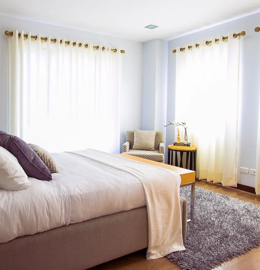 A sunlit bedroom with a carefully made bed