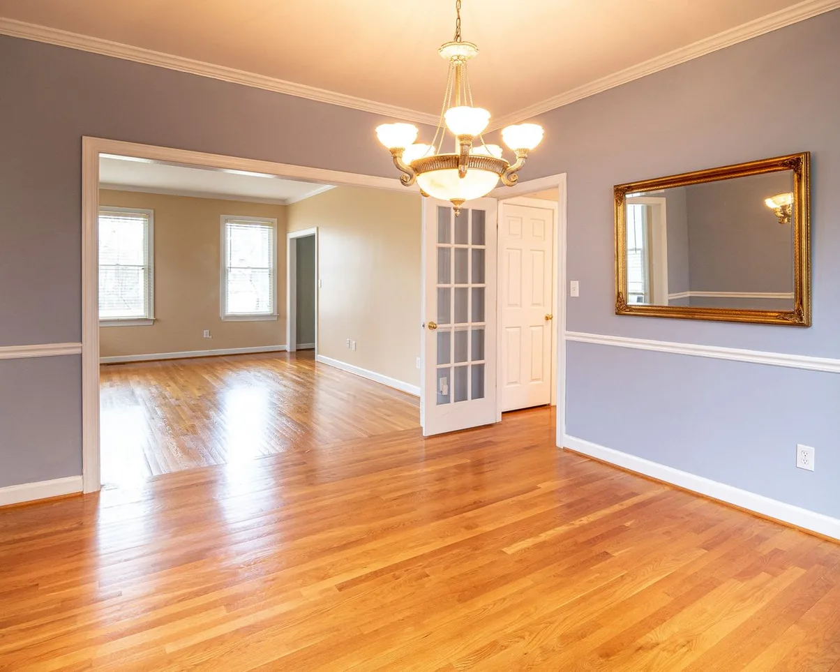An empty room with polished hardwood floors and a chandelier