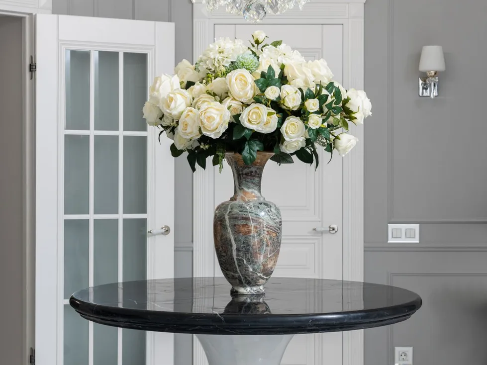 An entrance hall with a crystal chandelier and white roses on a round table